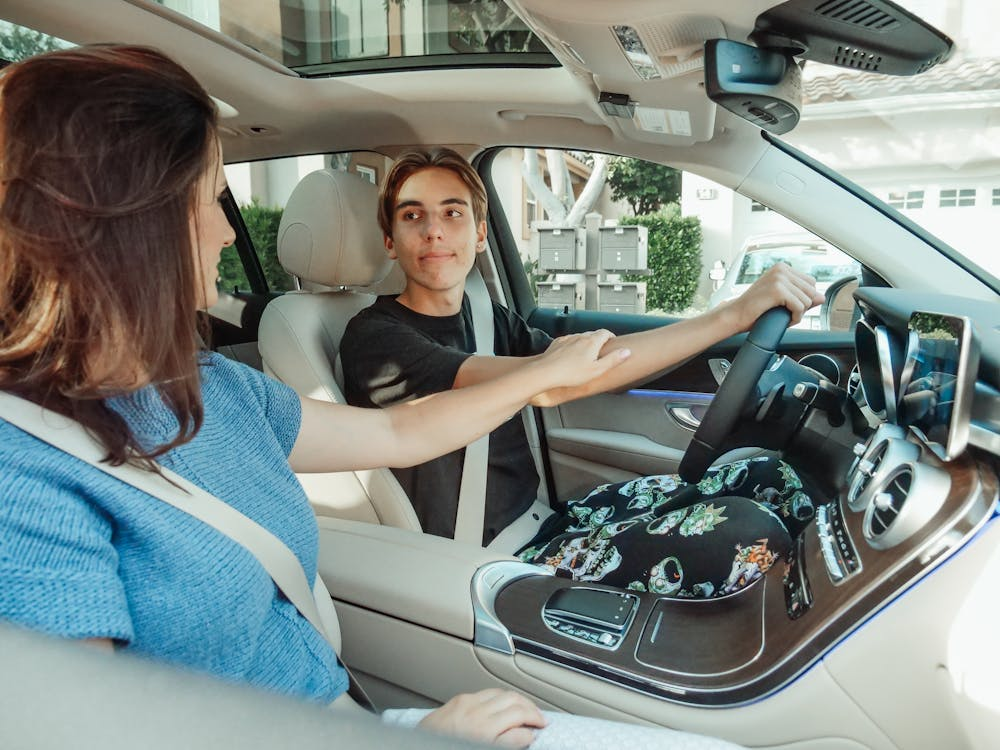 A Mother and Son inside a Car ready for a driving lesson