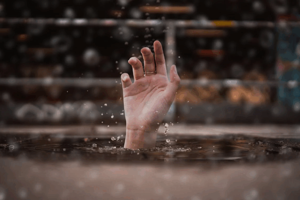 A hand reaching up from water, depicting someone struggling and seeking help, representing the escalation of domestic abuse when a victim attempts to gain independence.