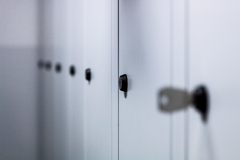 A row of white lockers with keys, symbolizing the importance of securing personal items and having safe storage when preparing to escape domestic violence.