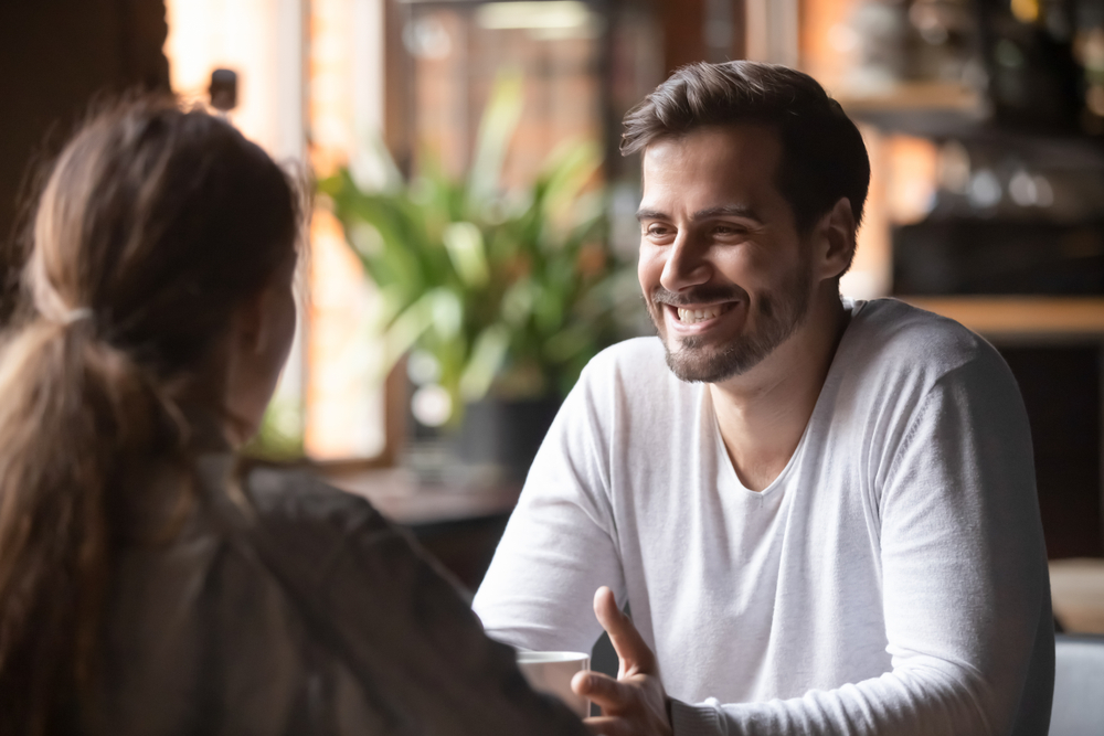 Rear view woman sitting at table in cafe with handsome smiling man, people spends time at meeting searching for soul mate, male telling about himself making good first impression, speed dating concept