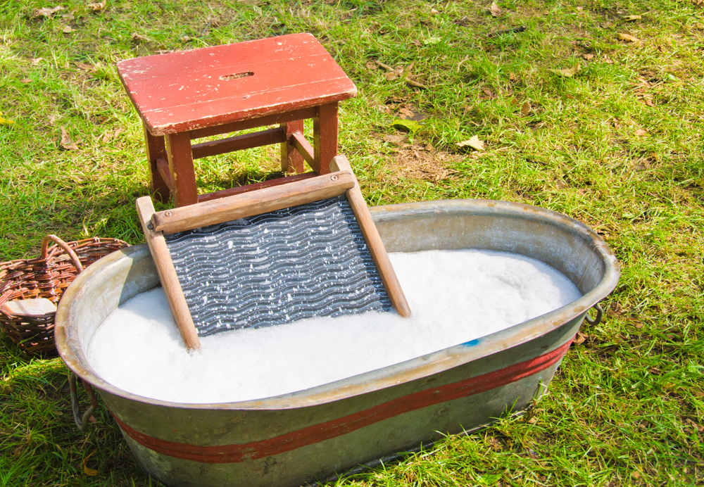 An old fashioned washing trougth filled with water, a vintage washboard and soap that wash the laundry