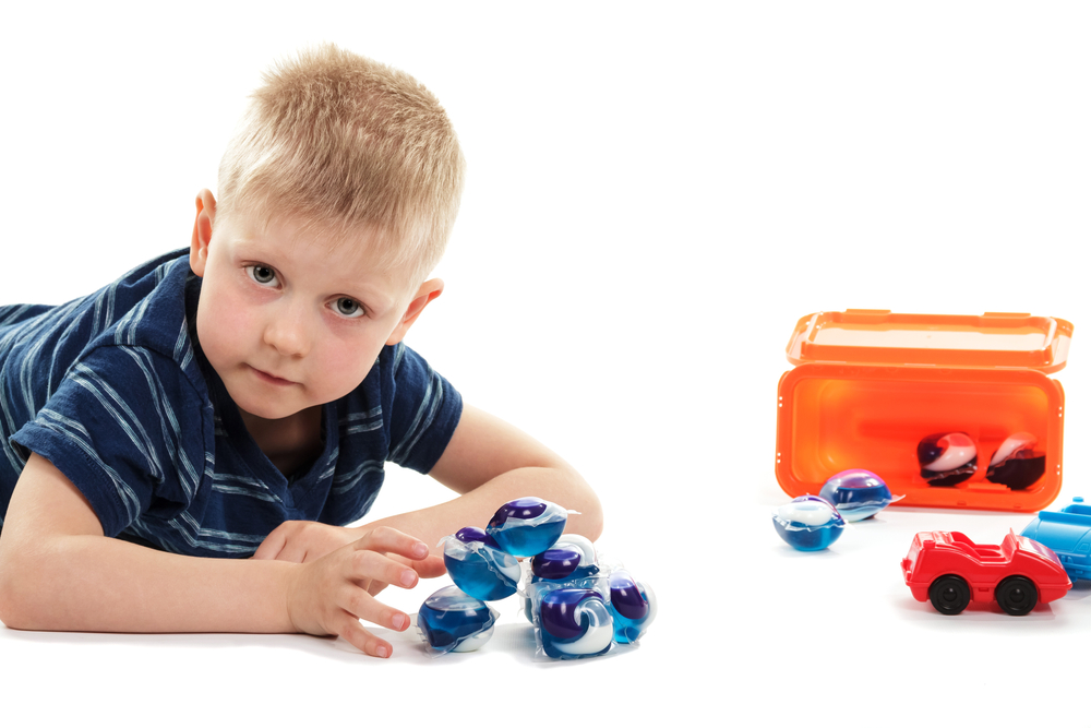 Unacceptable negligence. Child playing with toys and life-threatening capsules with washing concentrate