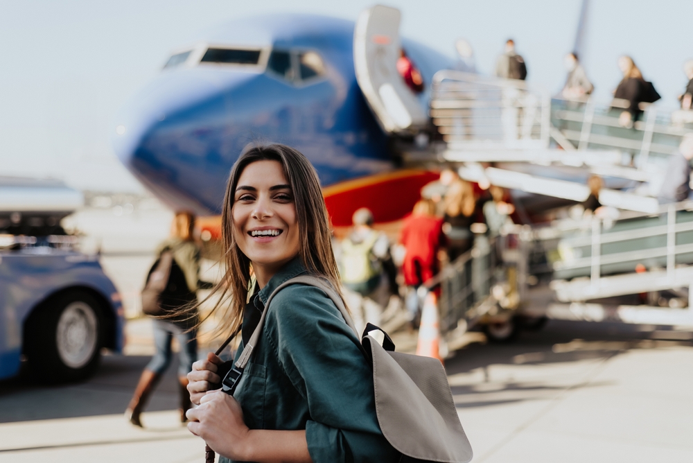 Woman tourist passager getting in to airplane at airport, walking from the terminal to the plane.
