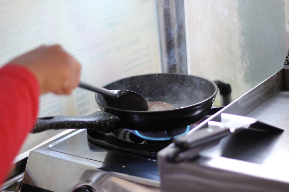 Hand cooking beef on pan. Smokey.