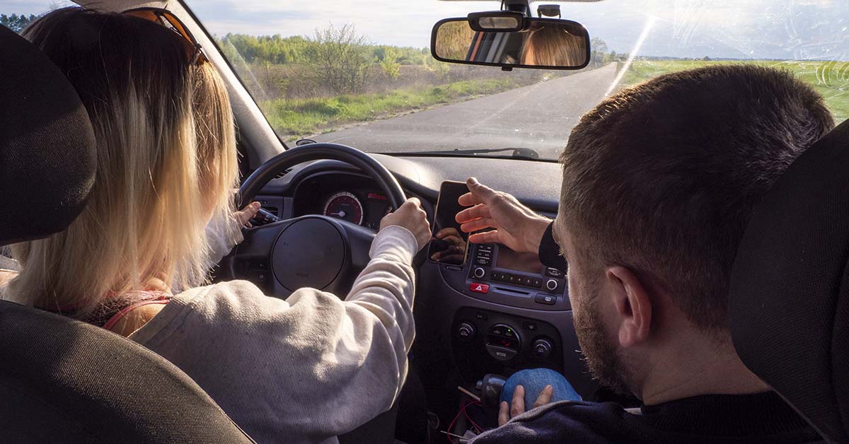 A driving instructor helps a woman learn how to drive a car. A woman is driving a car for the first time with an instructor and is very worried. Summer car driving training concept.