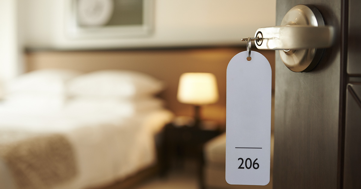 motel/hotel room, indicated by the presence of a bed, a nightstand with a lamp, and what looks like a key card holder or tag with the number "206" on it