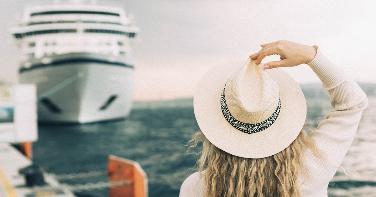 Woman standing at a doc with a cruise ship in the background