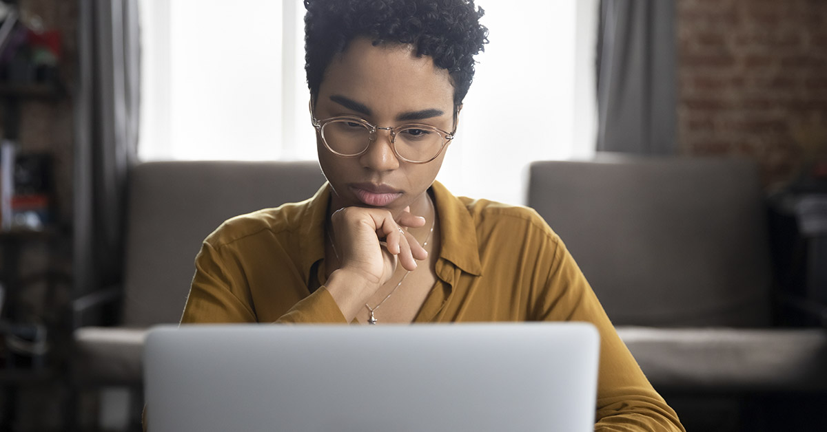 Pondering woman staring at laptop screen