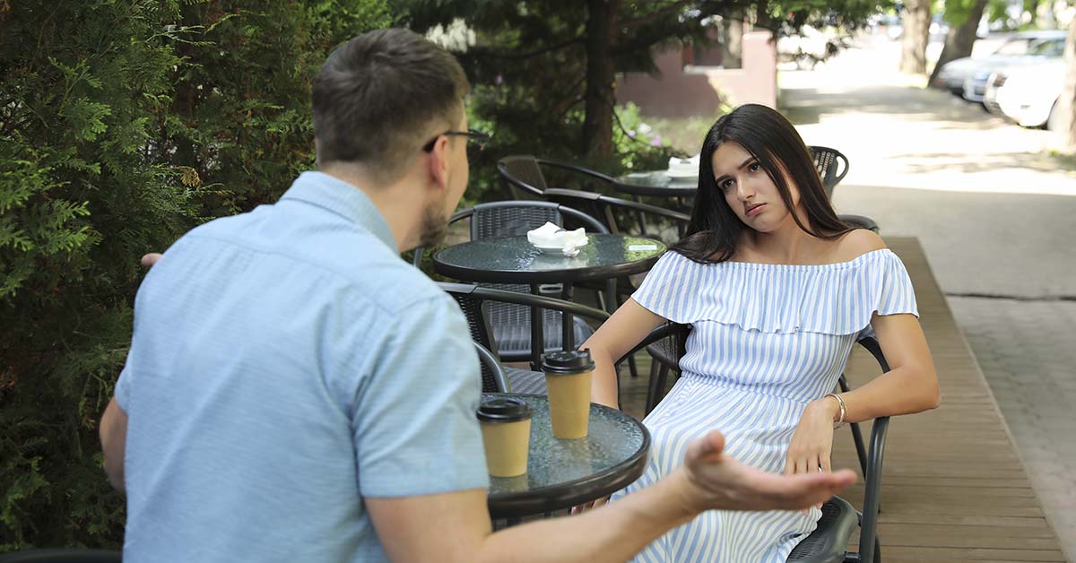 couple in dispute sitting at bistro table on side of the road