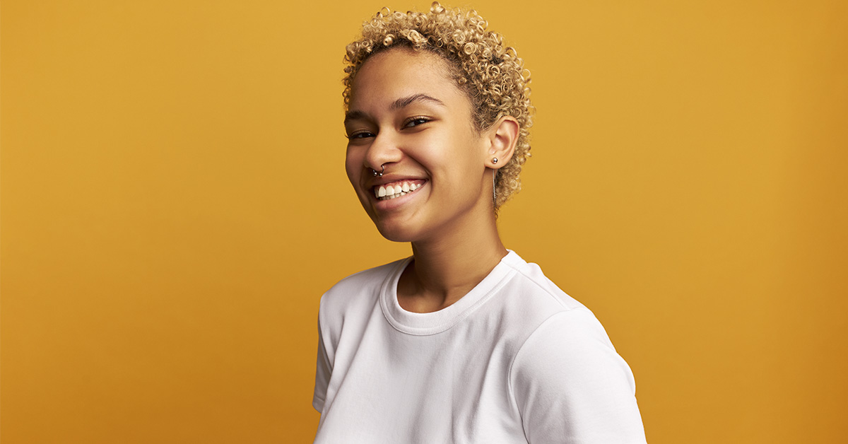smiling young woman with short hair. Orange/yellow background
