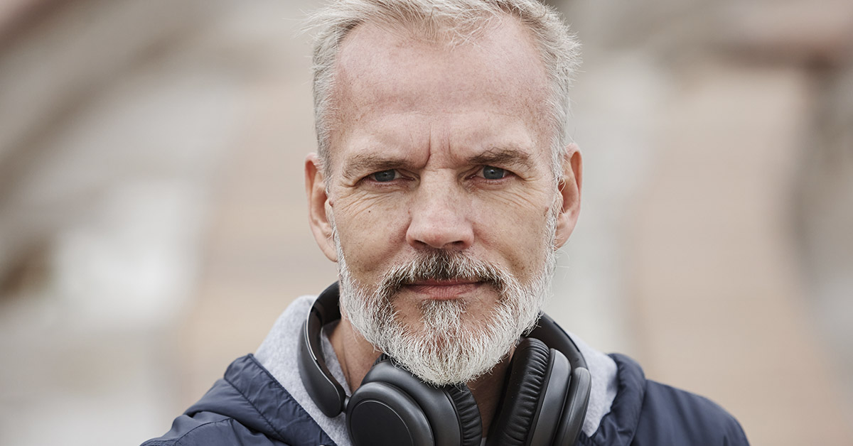 Middle aged man with headphones around neck. Gen X concept