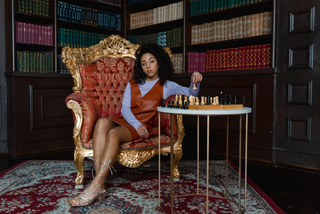 woman sitting in chair with chess set on table