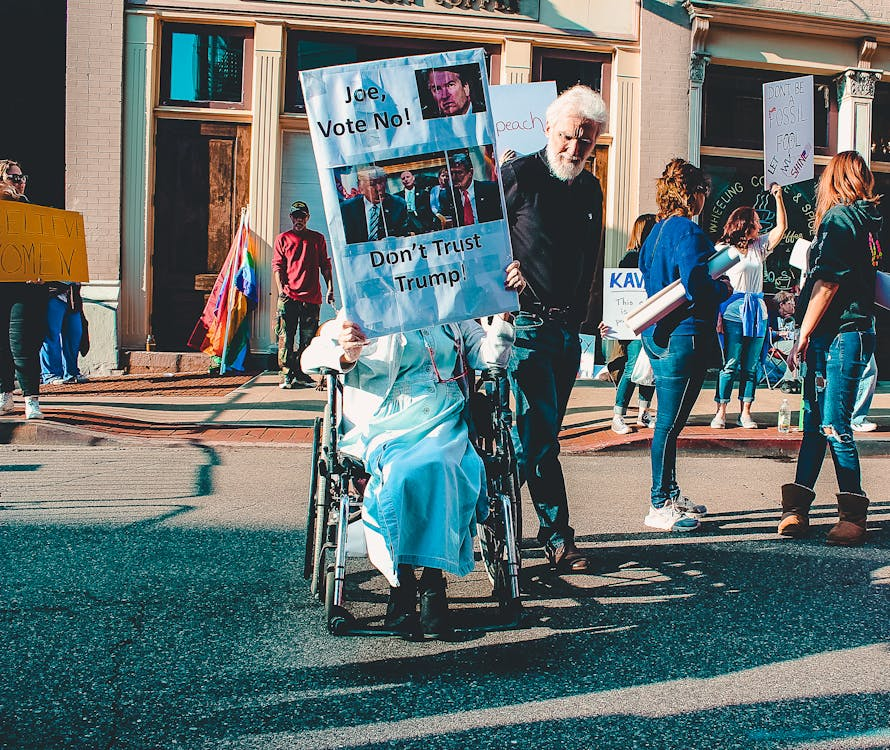 Man Standing Beside Person on Wheelchair