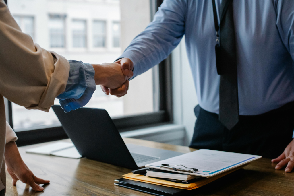Business handshake over documents and laptop, representing how couples can become transaction-focused roommates rather than emotionally connected partners.