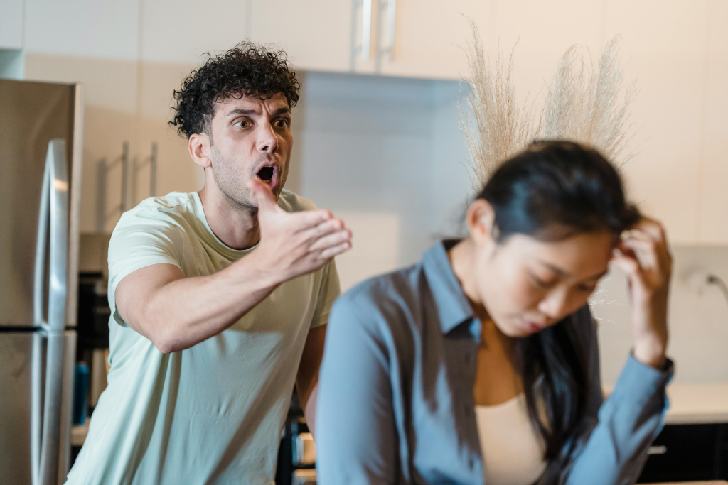Frustrated couple with man gesturing while woman holds her head, showing explosive conflict that results when relationship issues go unaddressed.