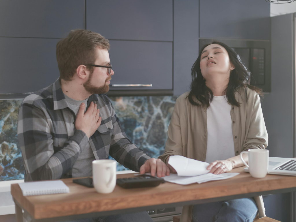 Tired couple at kitchen table with paperwork, exemplifying partners who function as efficient roommates rather than intimate lovers.