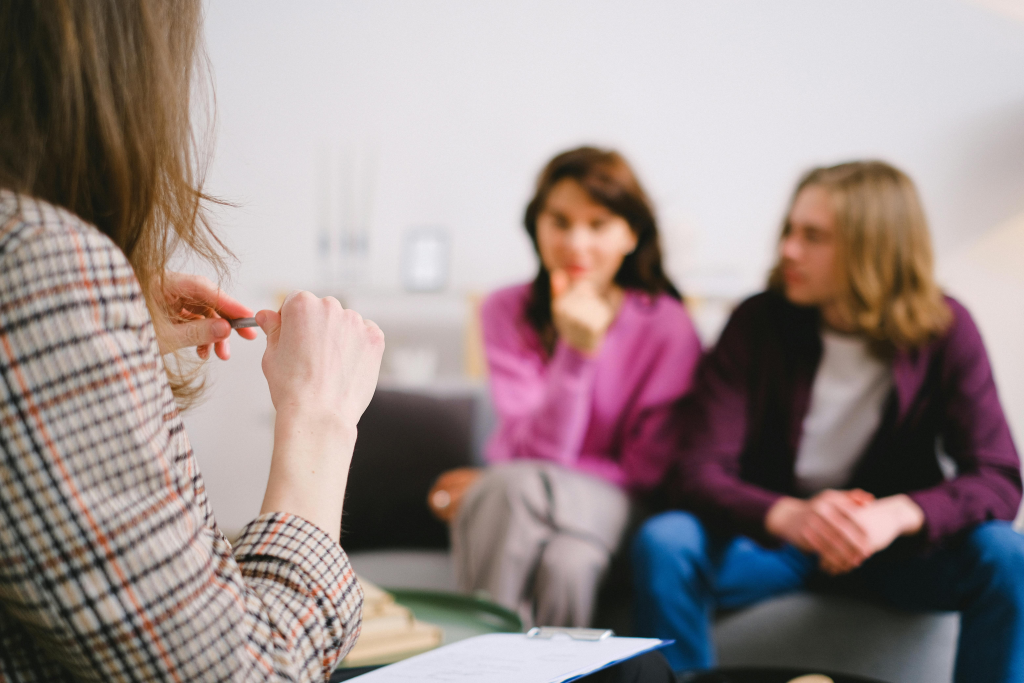 Couples who don't know how to talk through serious communication problems seek professional therapy help, shown with two people consulting a counselor in background.