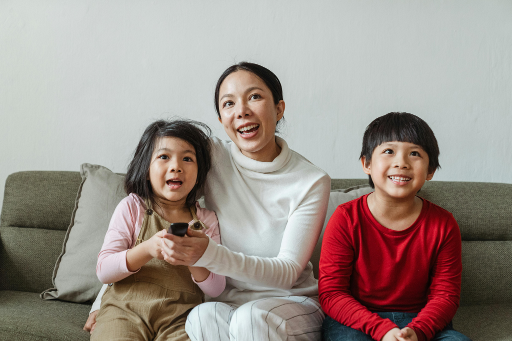 Mother and two children sitting together on couch watching screen time content.