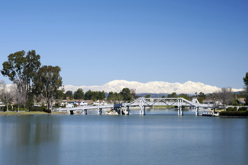 Irvine's recreational landscape with snow-capped mountains reflecting in calm lake water, illustrating the wellness infrastructure and outdoor access.