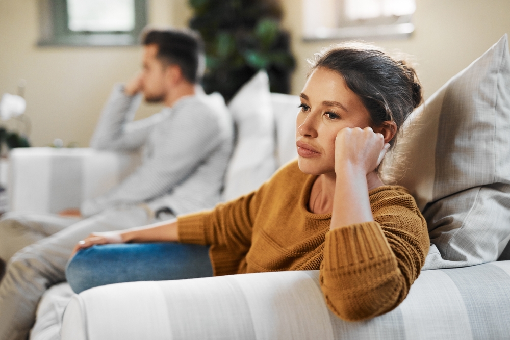Unhappy couple, argument and fight with living room, angry and drama in disagreement as partner. Woman, man and annoyed with frustrated, depressed and differences in home or lounge as married people