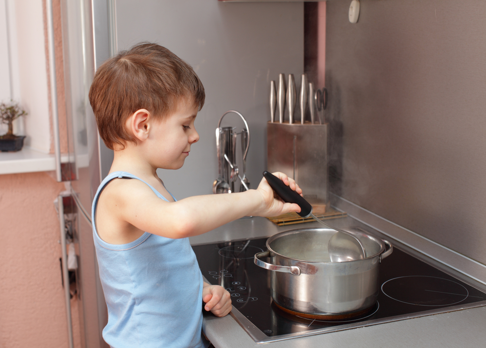 Little boy cooking porridge in kitchen