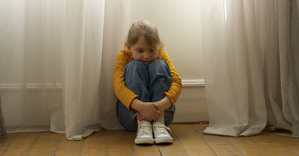 young girl sitting by window on the floor.