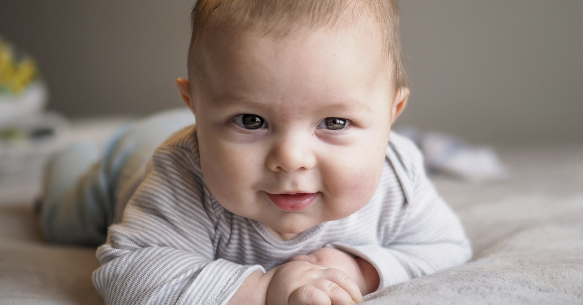 smiling baby laying on its tummy