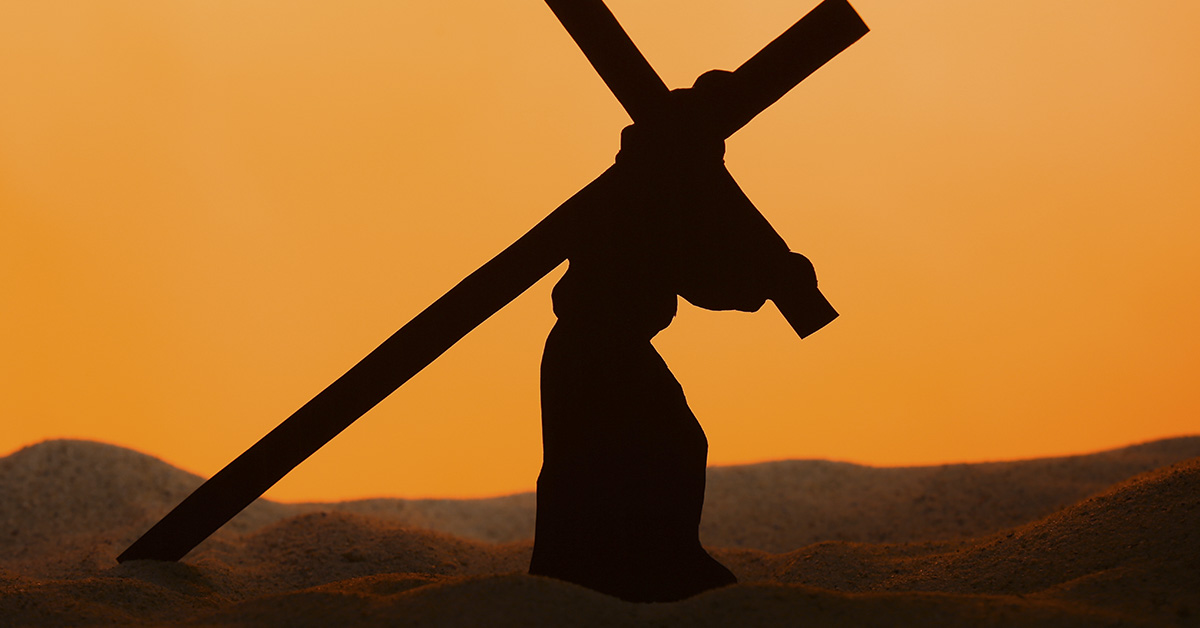 silouhette of person walking crucified to cross. Representation of Jesus