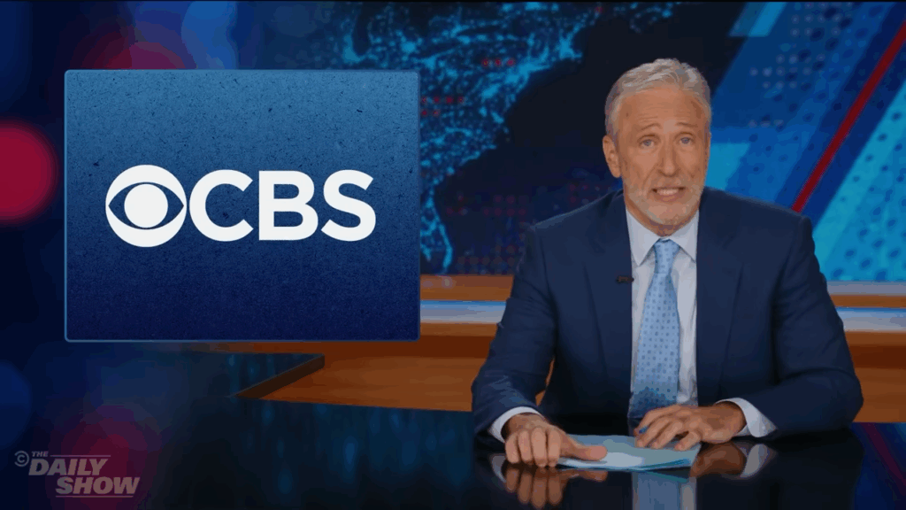 Jon Stewart at his Daily Show desk, speaking directly to camera during his monologue defending Stephen Colbert.