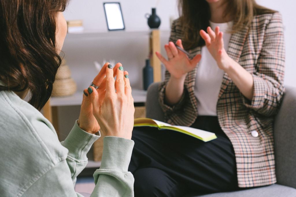 Two people with raised hands engaged in what appears to be therapeutic conversation or support.