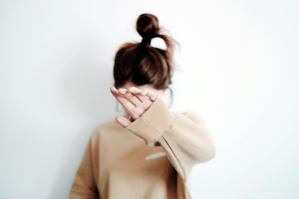 Person with hand extended forward in a defensive gesture, representing how unloved children learn to create barriers and protect themselves from potential emotional harm.