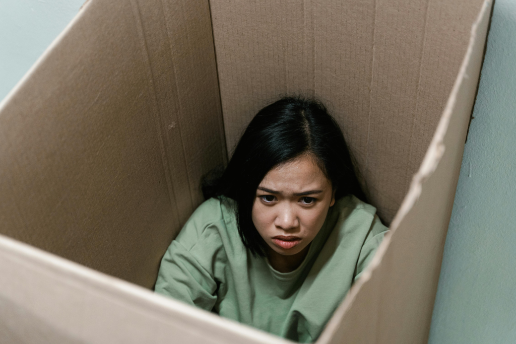 Unloved children may grow up feeling emotionally trapped and confined, represented by this individual sitting inside a cardboard box.