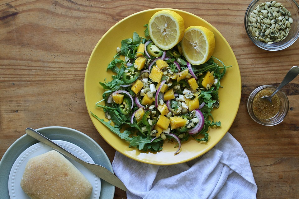 Hearty salad topped with lemon wedges on a sunny yellow plate, showing everyday meal ideas with fresh ingredients.