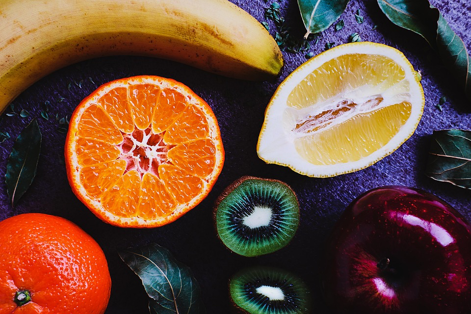 Colorful array of sliced fruits including orange, lemon, kiwi, and banana arranged artistically.
