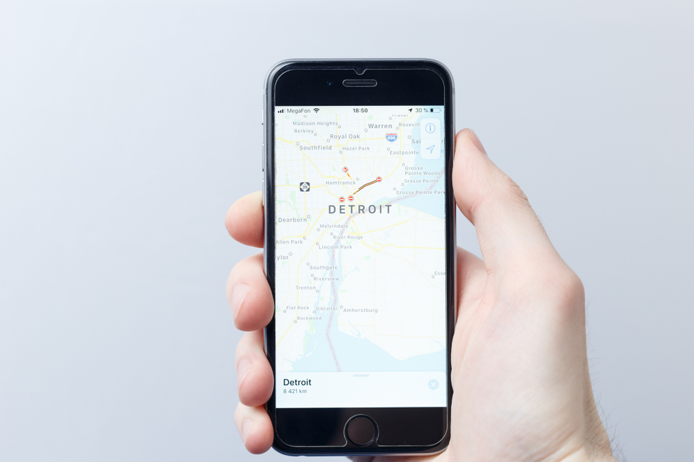Moscow / Russia - 03.30.2019: A hand holding a smartphone which displays city map with DETROIT. Illustrative editorial image on an white background. Travel concept

