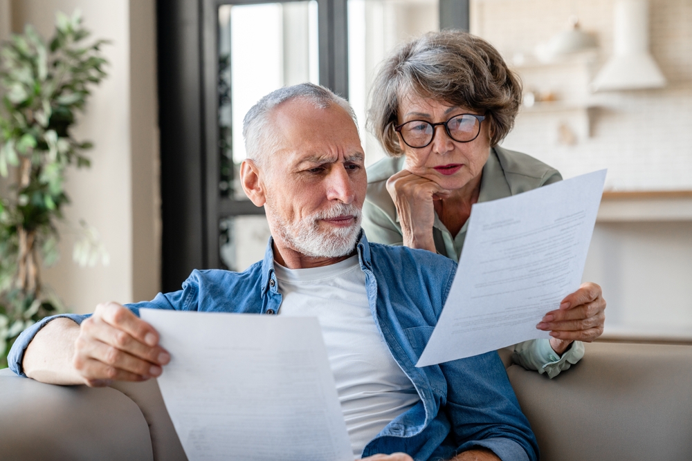 Senior old elderly spouses grandparents reading documents, having issue problem debt with money loss, doing paperwork together at home. Mortgage, loan and commerce procedures

