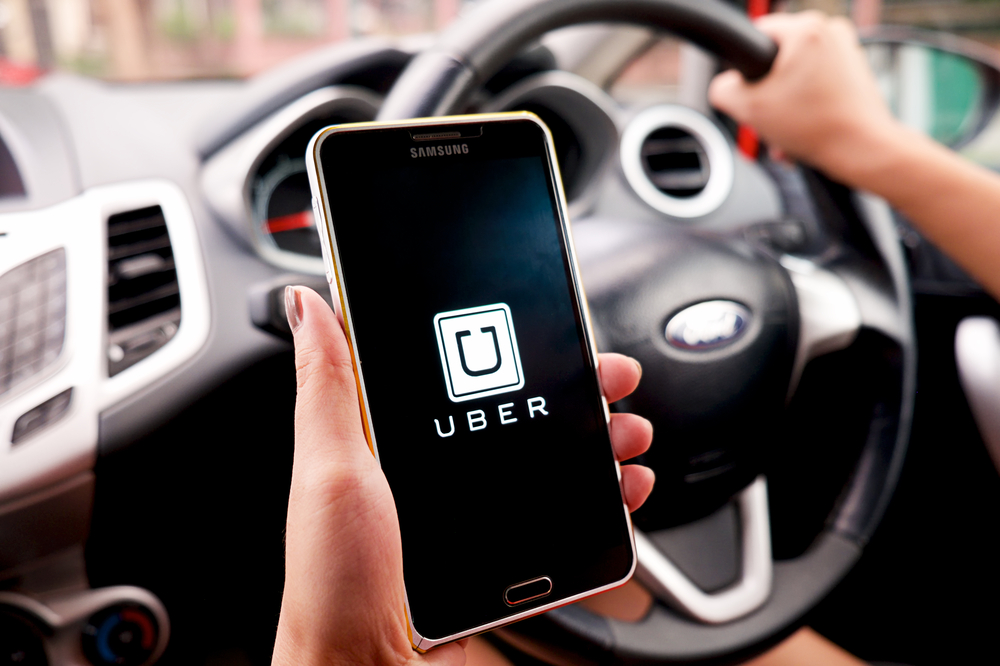 CHIANG MAI,THAILAND - SEP 16,2015 : A woman hand holding Uber app showing on Samsung note 3 in the car,Uber is smartphone app-based transportation network.
