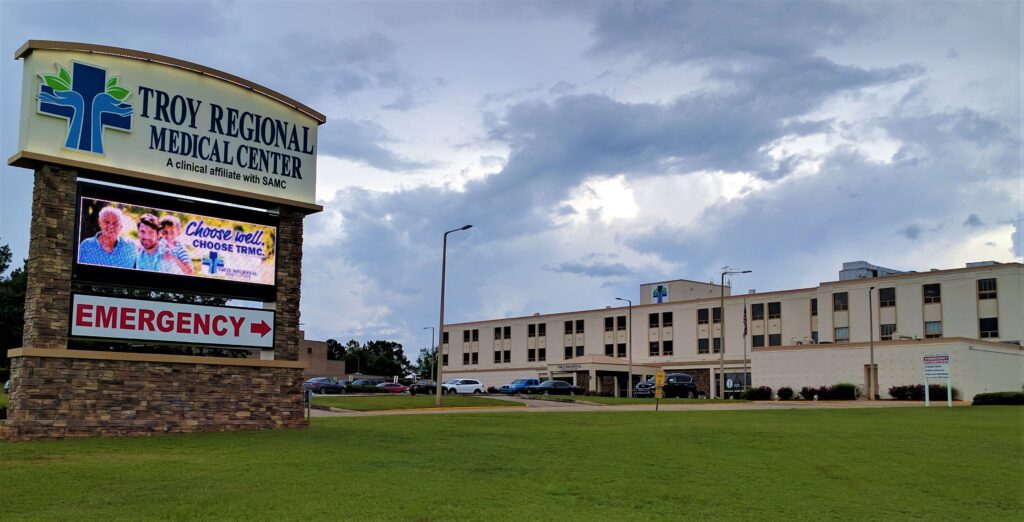 Troy Regional Medical Center sign and multi-story hospital building under cloudy sky.