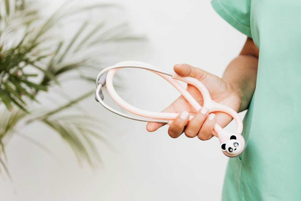 Healthcare worker in teal scrubs holding a stethoscope, symbolizing access to maternal care in Oklahoma.
