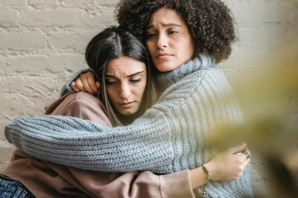 Two women embracing warmly, prioritizing connection over conflict.