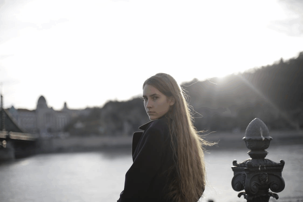 Woman in Violet Coat Standing Near Body of Water