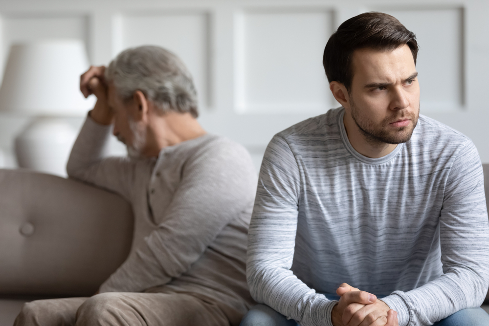 Mad thoughtful young man sit separately having fight misunderstanding with elderly father, angry stubborn mature dad and grown-up adult son avoid talking after quarrel, generation gap concept
