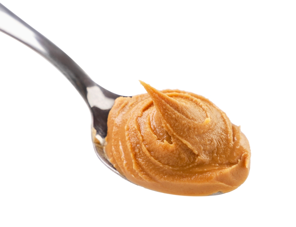 Peanut butter in a spoon close-up on a white background. Isolated