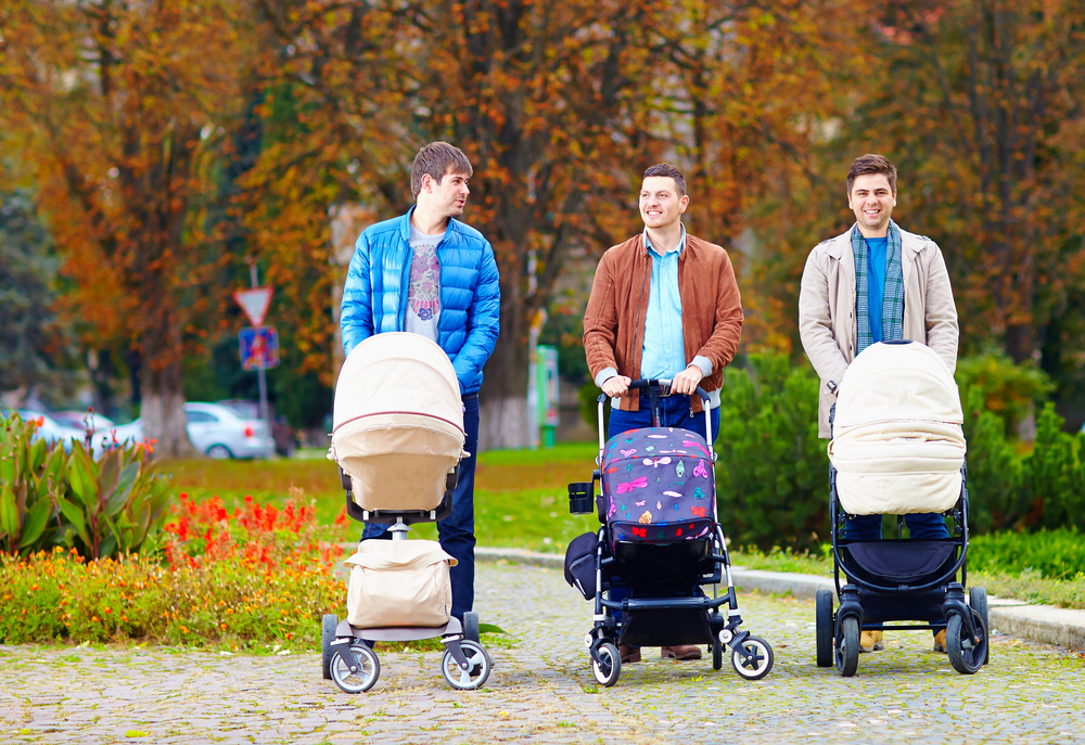 fathers walking with buggies in city park, parental leave
