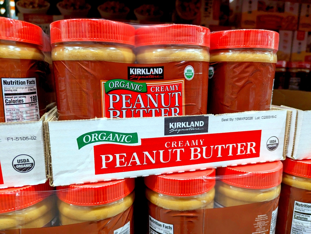 Raleigh, North Carolina - May 2 2025: Costco Kirkland Signature Organic Creamy Peanut Butter Jars on Shelf Logo Display 