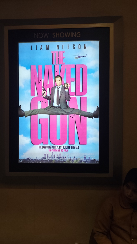 An Indonesian woman sitting under The Naked Gun movie poster at Yogyakarta, Indonesia, 30 July 2025
