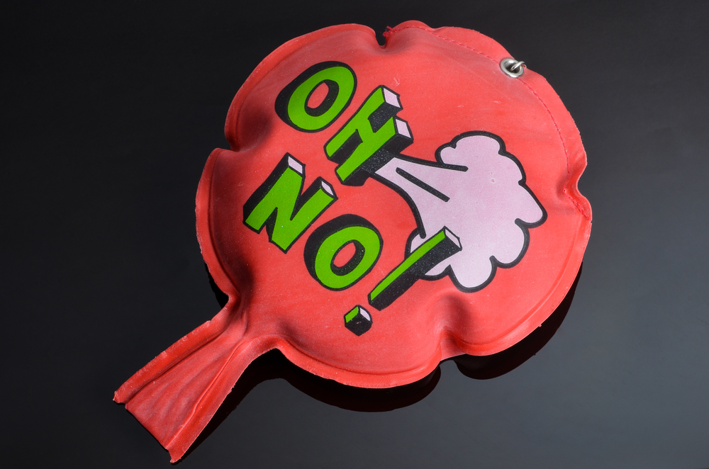 red rubber whoopee cushion with reflection on black glass
