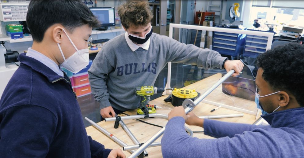 Bullis School students Evan Beach, Benjamin Gordon and Jewel Walker work on the wheelchair-stroller attachments for Jeremy King.