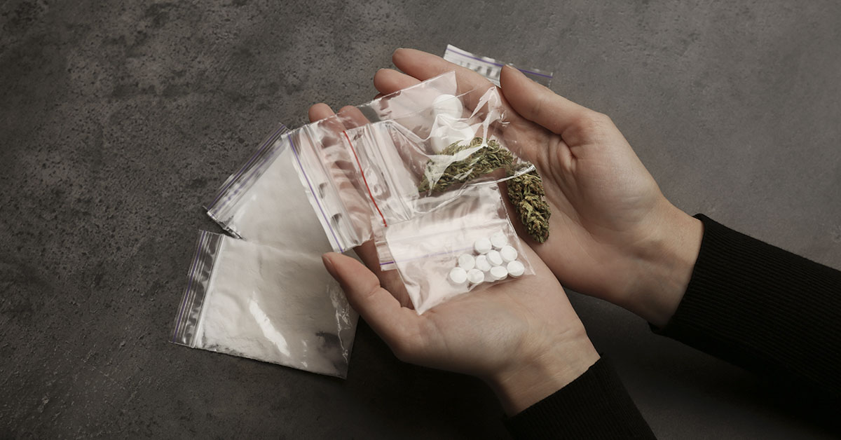 various small bags of street drugs on person's hands