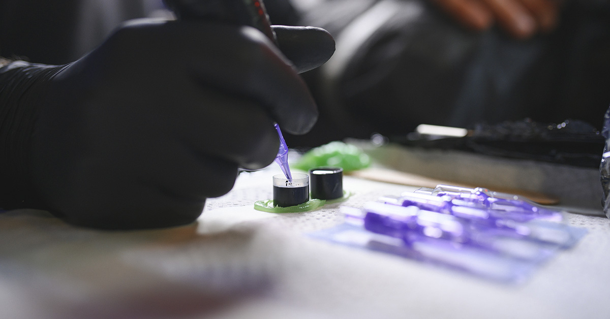 tattoo gun being dipped in ink